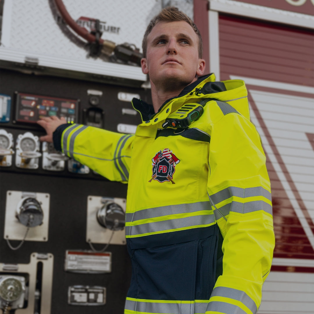 A firefighter wearing a hi-vis parka while operating machinery on a fire truck. Shop Fire & Resue.